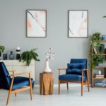 Posters and plants in bright living room interior with navy blue